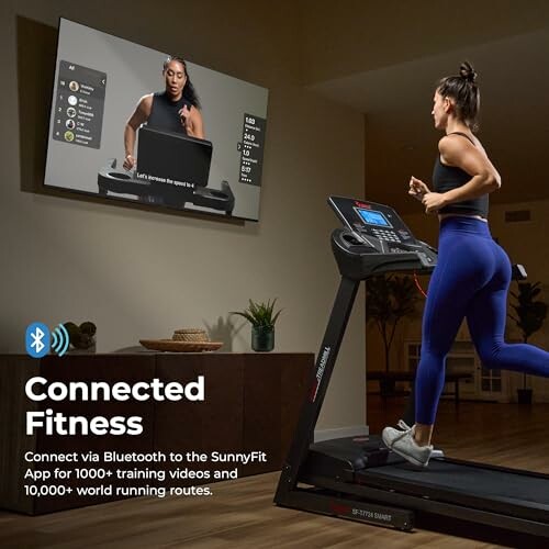 Woman running on a treadmill with a virtual fitness class on TV.