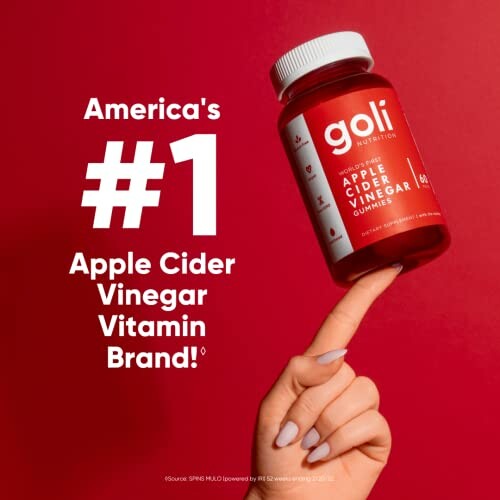 Hand holding Goli Apple Cider Vinegar Gummies bottle against red background. 