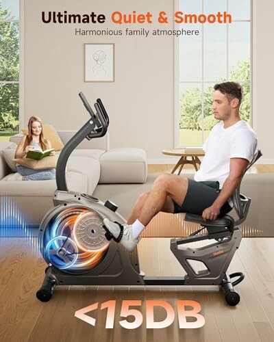 Man on exercise bike in living room with woman reading on couch.