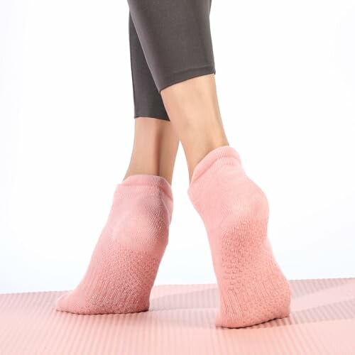 Person wearing pink grip socks on a yoga mat.