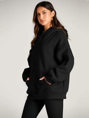 Woman wearing a black hoodie with hands in pockets